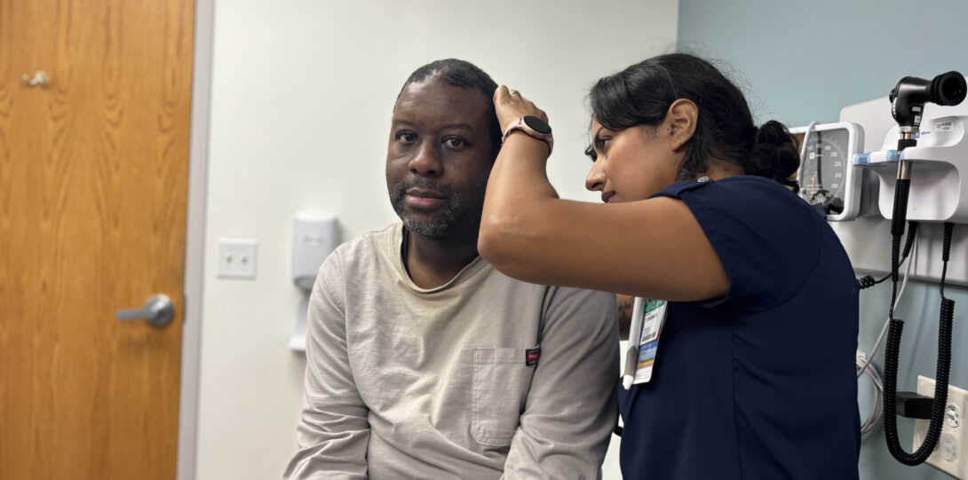 Photo of a medical student examining patient's ear.